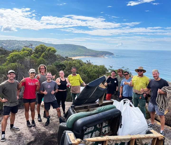 Group of smiling volunteers posing on cliff top with collected rubbish